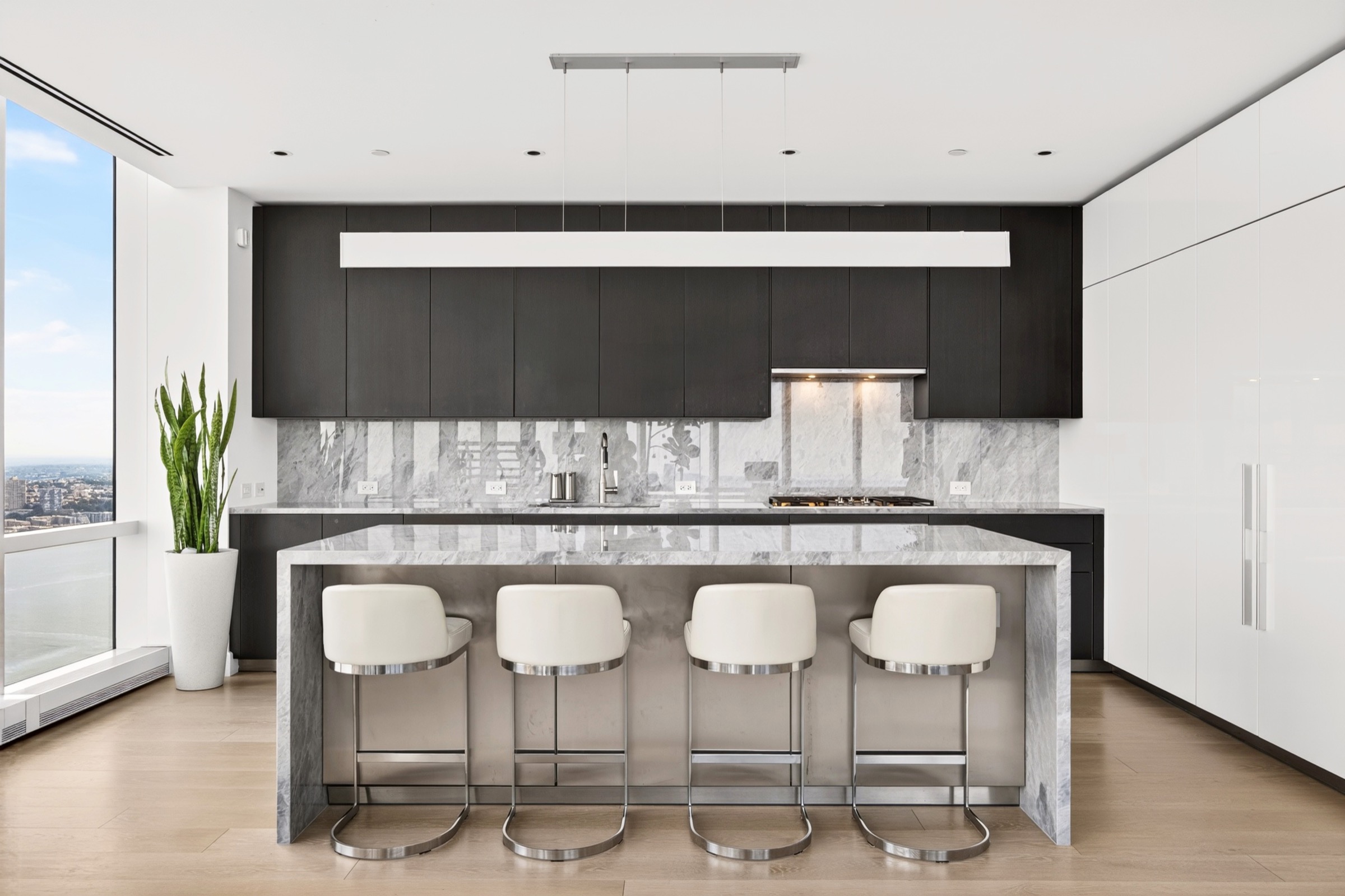 Dark kitchen with marble island and city views