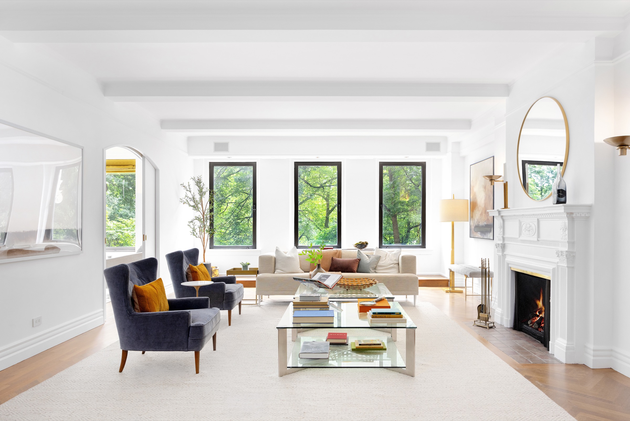 Sunlit living room with park views through three tall windows